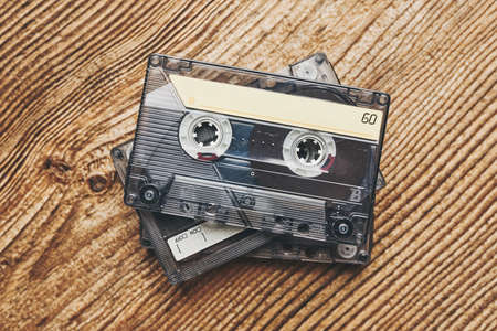 Tape cassettes. Magnetic cassette tapes on wooden table. Retro music style. 80s music party. Vintage style. Analog equipment. Stereo sound. Back to the pastの写真素材