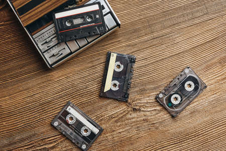 Compact cassette tapes and cassette recorder on wooden table. Retro music style. 80s music party. Vintage style. Analog equipment. Stereo sound. Back to the pastの写真素材