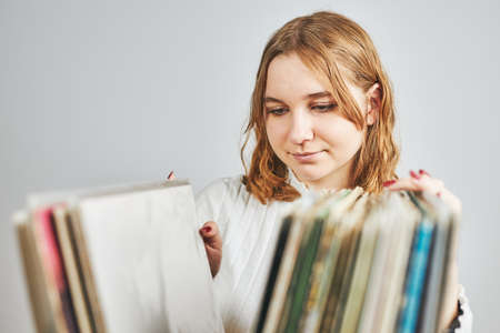 Playing vinyl records. Listening to music from vinyl record player. Retro and vintage music style. Young woman searching analog LP record album in stack of old records. Music collection. Music passionの写真素材