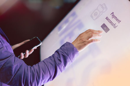 Woman buying event tickets using a touchscreen kiosk and online payment. Online shopping. Contactless payments. Personal banking. Modern payment methods. Touchscreen with a ticket purchasing appの写真素材