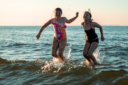 Children playing by the shore of the Baltic Sea in Poland. Girls playing in the water during summer vacation. Family holiday by the sea. Active leisure time. Joyful summer moments. Playing with inflatable toyの写真素材
