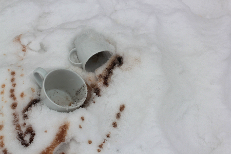 two white cups and the poured coffee in snowの写真素材