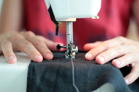 Close-up seamstress hands working on sewing machine at home. Sewing process. woman hands behind sewing close-up.の写真素材