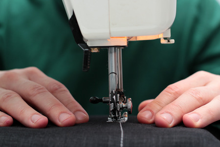 Close-up seamstress hands working on sewing machine at home. Sewing process. woman hands behind sewing close-up.の写真素材
