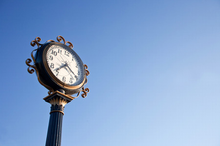 vintage style clock post with blue skyの写真素材