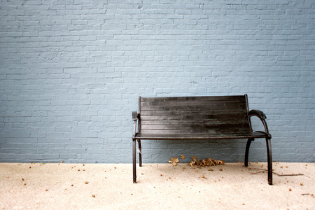 old black bench with painted brick wallの写真素材