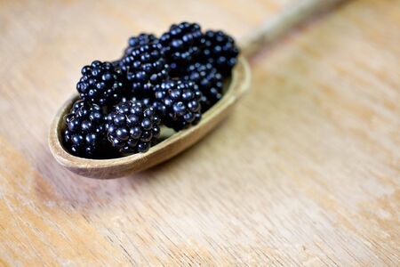 close up of wild blackberries in wooden spoonの写真素材