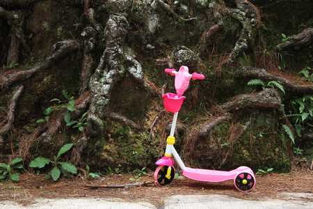 pink scooter in the side of roadの写真素材