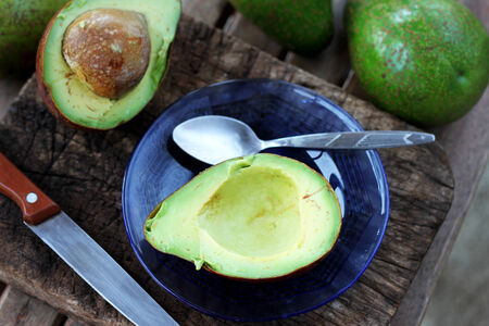 Sliced avocado on old wooden chopping boardの写真素材