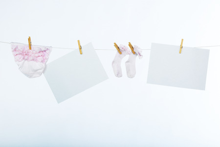 Two clean sheet of paper and baby?s clothes hanging on the clotheslineの写真素材