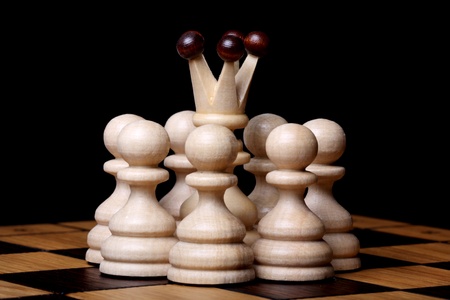 White queen among pawns on a chess board. Isolated on blackの写真素材