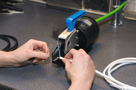 Crimping of bushings at the ends of an electric cable in the manufacture of an electric mat