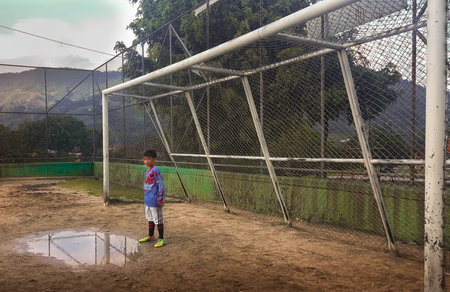 MEDELLIN, COLOMBIA - NOVEMBER 21, 2019: A boy from a community soccer school standing under a soccer goal looking at the cameraのeditorial素材