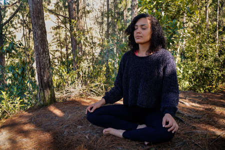 Young latin woman in meditation posture in the forestの写真素材