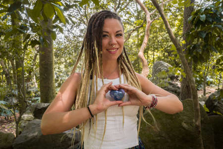 Caucasian woman with dreadlocks smiling and holding a blue stone heart in her hands. Blonde dreadlocksの写真素材
