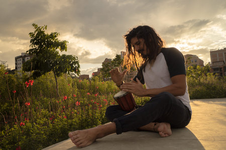 Man playing the drum in the park at sunset