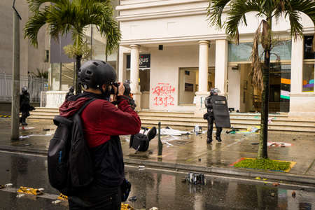 MEDELLÃN, COLOMBIA - APRIL 28, 2021: Reporter photographing police in demonstrations in Colombia for the national strikeのeditorial素材