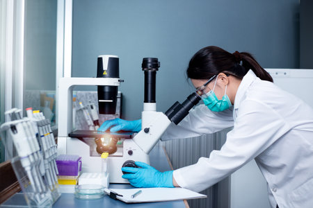 Chemical Advanced Research Laboratory, portrait of a female researcher using the microscope to look at culture cells on the microscope slide. Research for pharmaceutical, medicine, and biotechnology development.の写真素材