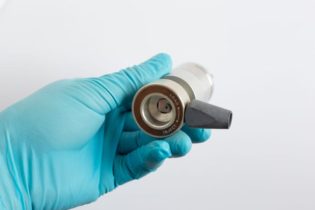A scientist's hand in a blue glove holds a manual HPLC injection valve. The view shows the LOAD and...