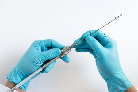 A scientist's hands in blue gloves connect a stainless steel capillary fitting to an HPLC column for liquid chromatography analysis in a science lab on a white background.の写真素材