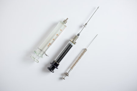 Three types of glass syringes for sample injection in HPLC and instrumental analysis, including 100 microliter, 10 mL, and 20 mL syringes, on a white background.の写真素材
