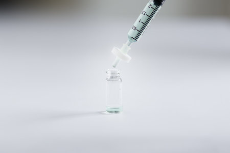 closeup of syringe sample solution with attached filter dispensing liquid sample into glass autosampler vial. This filtration step removes particulates during sample preparation for HPLC or LC-MS.の写真素材