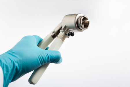 A scientist's hand holds a manual vial crimper used to seal aluminum caps onto glass autosampler vials in the laboratory.の写真素材