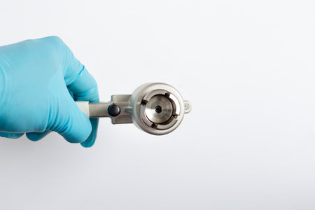 Close-up view of a scientist's hand holding a manual vial crimper, clearly showing the crimping head for sealing aluminum caps onto glass autosampler vials in a laboratory.の写真素材