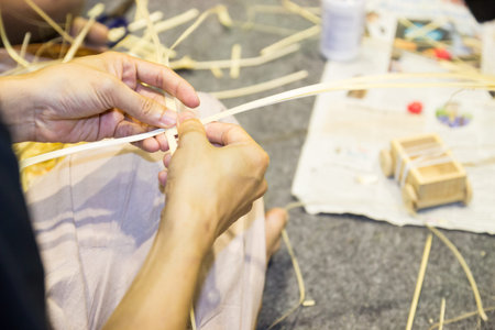 closeup of artisan's hand weaves the decorative traditional handmade rattan product