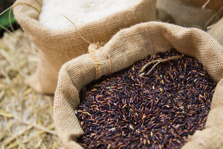 brown and white rice in the burlap sackの写真素材