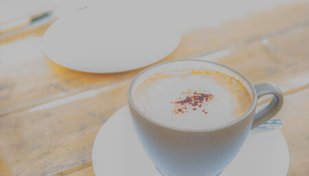 high key and soft focus image of a cup of espresso coffee on saucer on wooden tableの写真素材