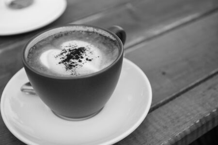 a cup of espresso coffee on saucer with heart-shape foam on top on wooden tableの写真素材