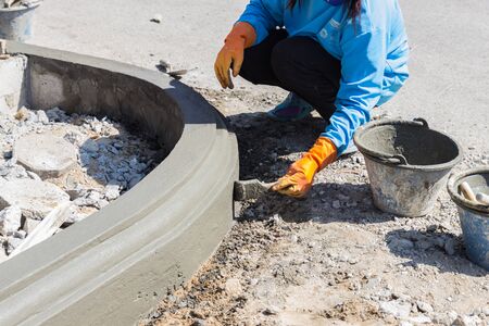 Chiangmai, Thailand - November 25, 2014: The woman worker apply cement over the surface of footpath edge at Suandok temple.のeditorial素材