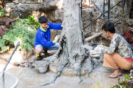 Uttaradit, Thailand - December 19, 2014: The workers are grout cement on the fake tree trunk in Lomyen shop.のeditorial素材