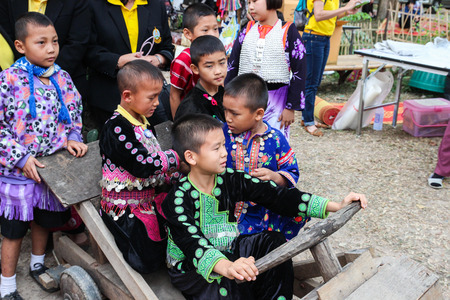 Chiangmai, Thailand - December 18, 2014: thailand hill tribe boy with traditional northern tribe costume on wooden car toy in royal project fair at Chiangmai university.のeditorial素材