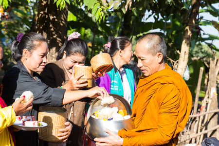 Sakon Nakhon, Thailand - December 20, 2014: People put food on buddhist monk alms bowl in Sakon Nakhon, Thailand on December 20, 2014.のeditorial素材