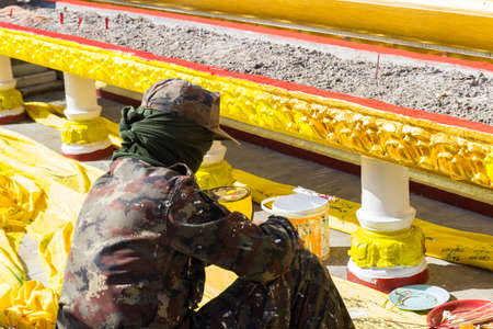 The worker is painting gold color on joss stick pot in Pratart Phanom temple in Nakhon Phanom, Thailand.のeditorial素材
