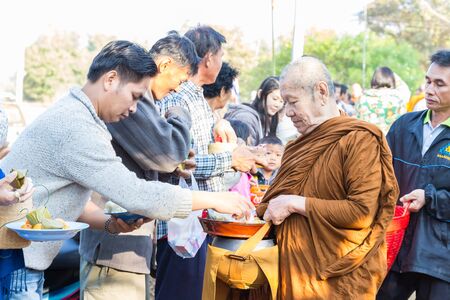 Sakon Nakhon, Thailand - December 21, 2014: People offer food on buddhist monk alms bowl in Sakon Nakhon, Thailand on December 21, 2014.のeditorial素材