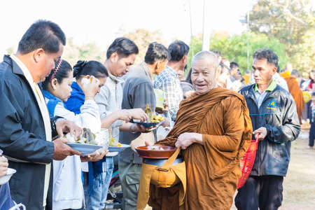 Sakon Nakhon, Thailand - December 21, 2014: People offer food on buddhist monk alms bowl in Sakon Nakhon, Thailand on December 21, 2014.のeditorial素材