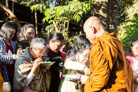 Sakon Nakhon, Thailand - December 21, 2014: People offer food on buddhist monk alms bowl in Sakon Nakhon, Thailand on December 21, 2014.のeditorial素材