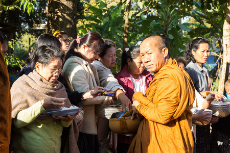 Sakon Nakhon, Thailand - December 21, 2014: People offer food on buddhist monk alms bowl in Sakon Nakhon, Thailand on December 21, 2014.のeditorial素材