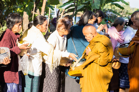 Sakon Nakhon, Thailand - December 21, 2014: People offer food on buddhist monk alms bowl in Sakon Nakhon, Thailand on December 21, 2014.のeditorial素材