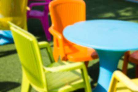 blurry defocused yellow, orange, blue plastic desk and chair for backgroundの写真素材