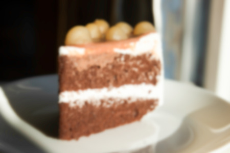 blurry defocused image of chocolate cake with cream and Macadamia on top for backgroundの写真素材