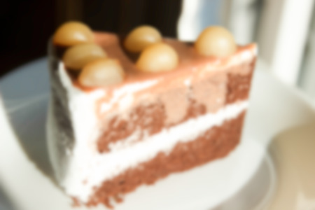 blurry defocused image of chocolate cake with cream and Macadamia on top for backgroundの写真素材