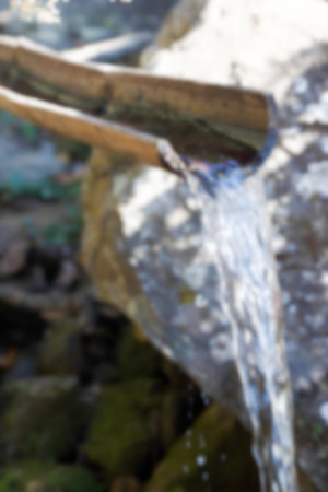 blurry defocused image of water flowing through bamboo billet in the garden for background