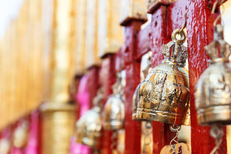 golden brass bell hanging on the red asian temple fenceの写真素材