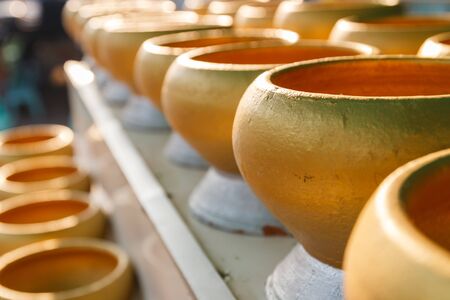 row of golden buddhist monk alms bowl for people to donate money in templeの写真素材