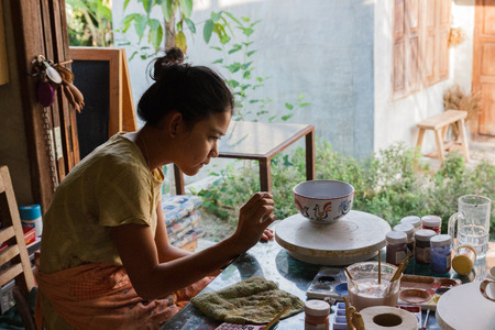 Chiang Mai, Thailand - April 26, 2015: The girl is painting the bowl in Baankangwat shopping center and restaurant for travelling attraction.のeditorial素材