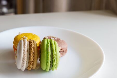 orange, white, brown green macaroon on white plateの写真素材